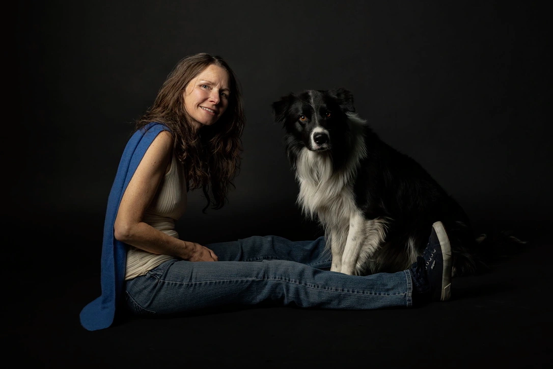 Frau mit schwarz weißem Border Collie mit dunklem Hintergrund