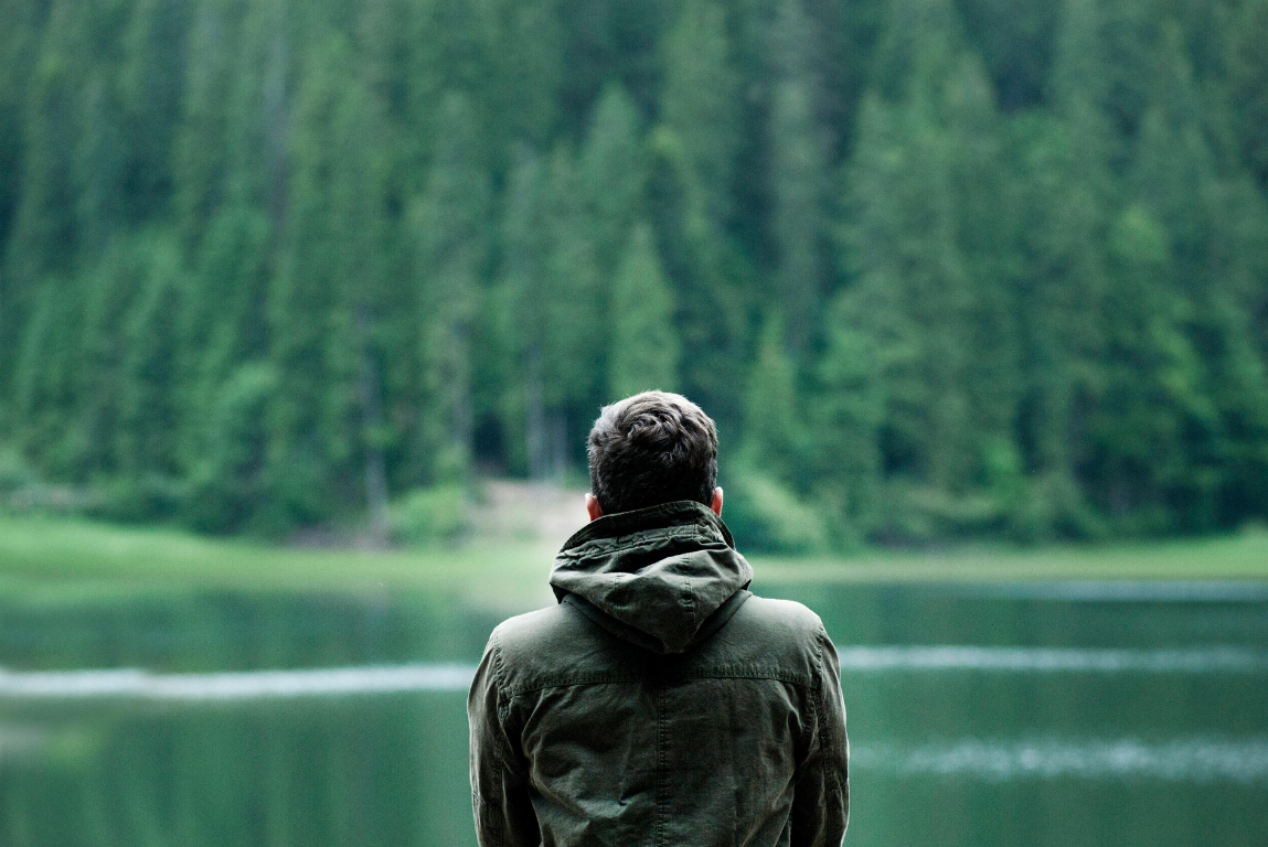 Person in Jacke blickt auf einen ruhigen Waldsee – Symbolbild für Hanf ohne Rausch
