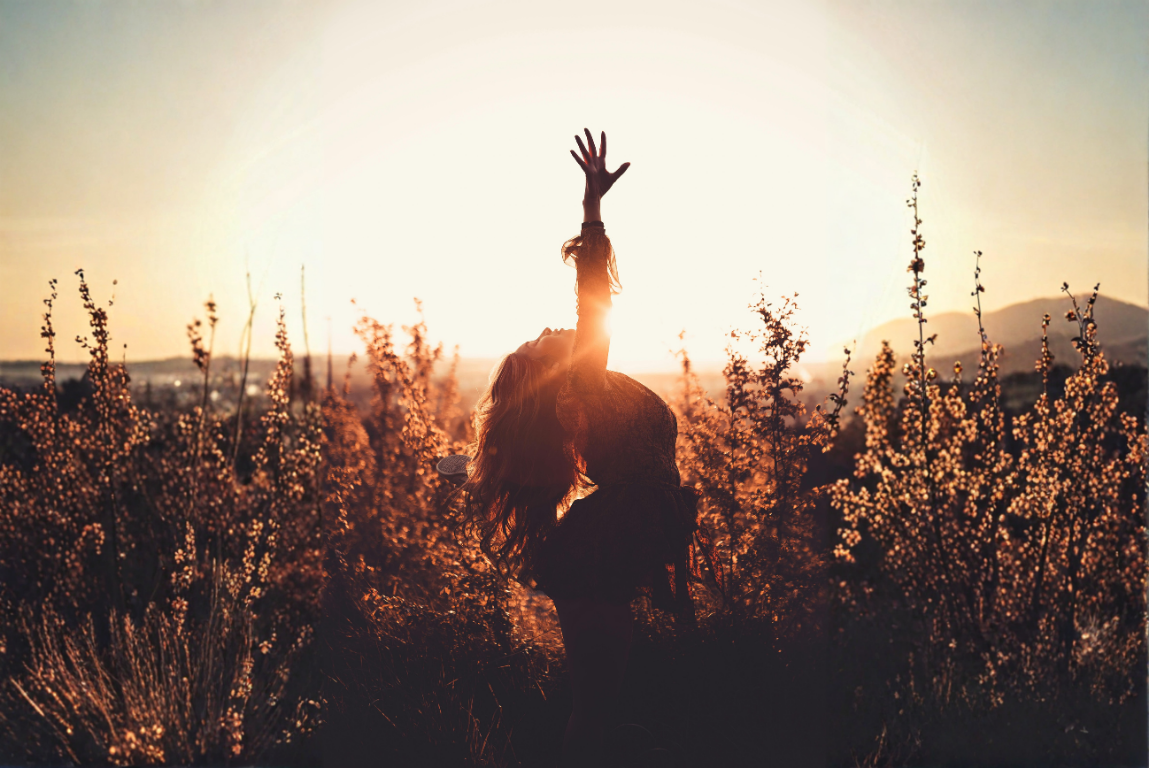 Frau hebt die Hand im goldenen Sonnenlicht – Symbolbild für Hanf ohne Rausch. Foto von Mauro Savoca / Pexels